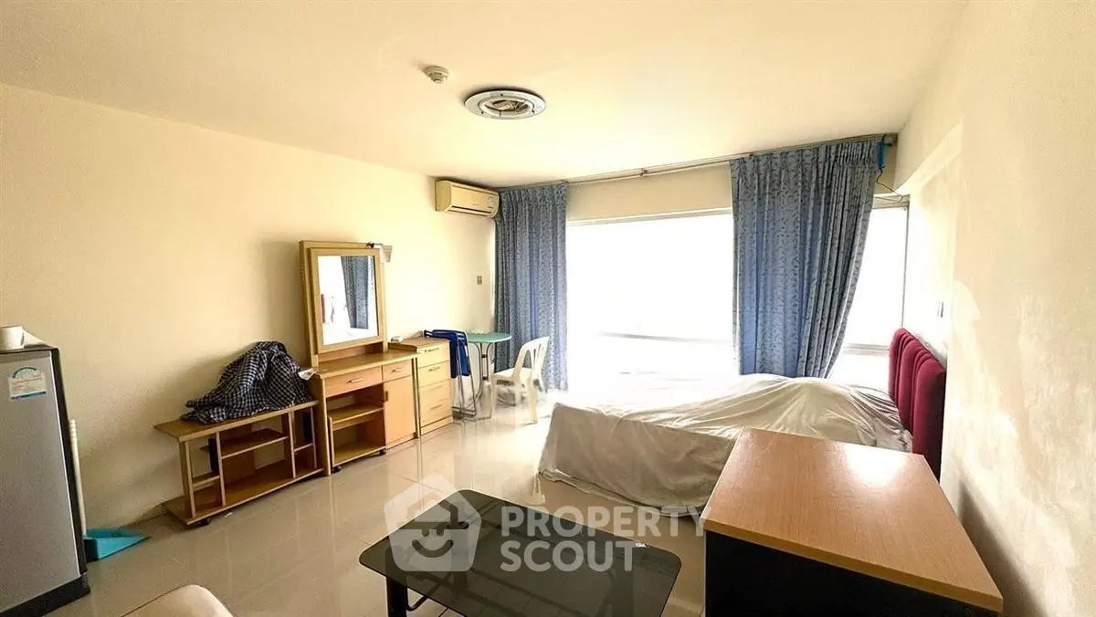 Spacious bedroom with large window and minimalist furnishings in modern apartment.
