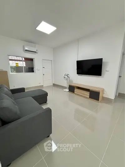 Modern living room with sleek furniture and wall-mounted TV, perfect for relaxation.