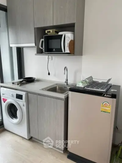 Modern compact kitchen with washing machine and microwave in sleek apartment