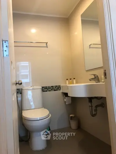 Modern bathroom with sleek fixtures and neutral tones, featuring a wall-mounted sink and a toilet.