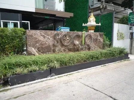 Modern building entrance with stylish signage and lush greenery
