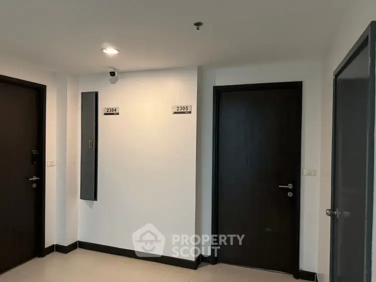 Modern apartment hallway with two dark wooden doors and room numbers 2304 and 2305.
