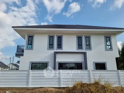 Modern two-story house with sleek design and large windows under a clear blue sky.