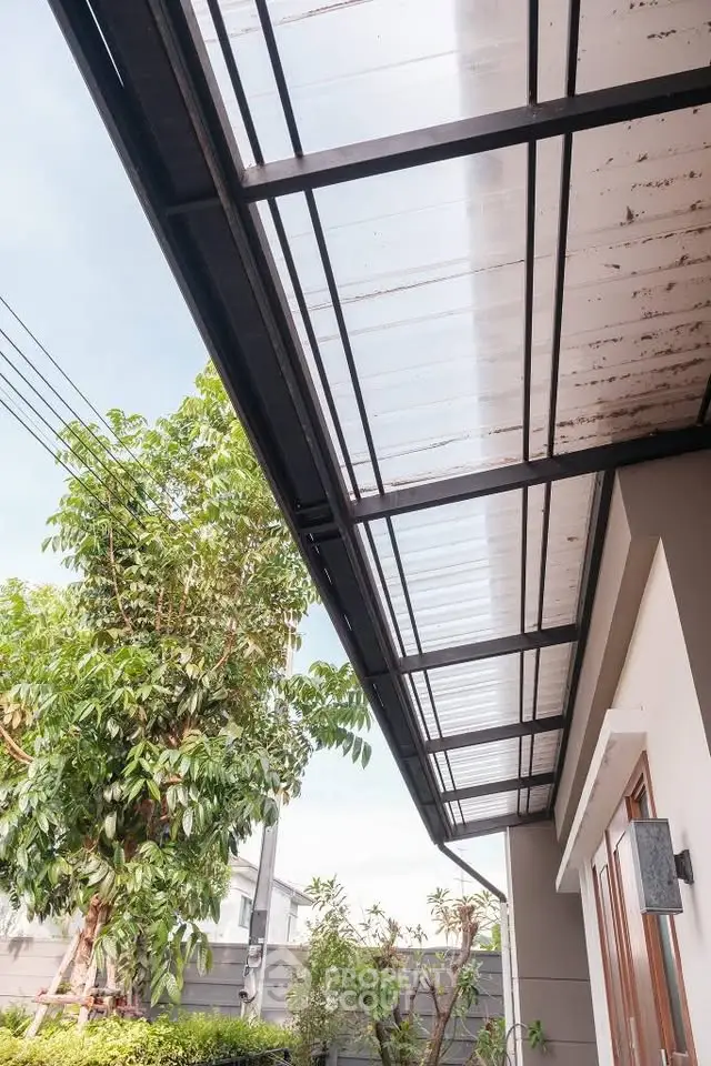 Modern house exterior with sleek glass canopy and lush greenery