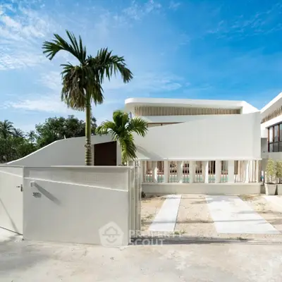 Modern architectural home with sleek design and palm trees, showcasing luxury and elegance in a serene setting.
