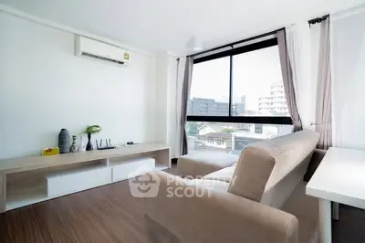 Modern living room with large window and stylish furniture in a bright apartment.