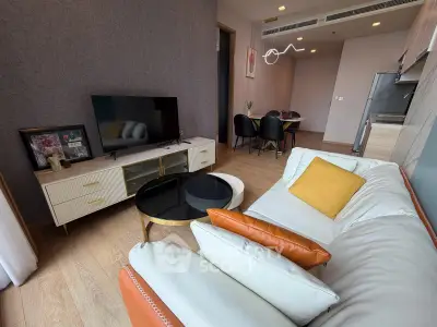 Modern living room with stylish decor and open dining area, featuring a cozy sofa and sleek TV unit.