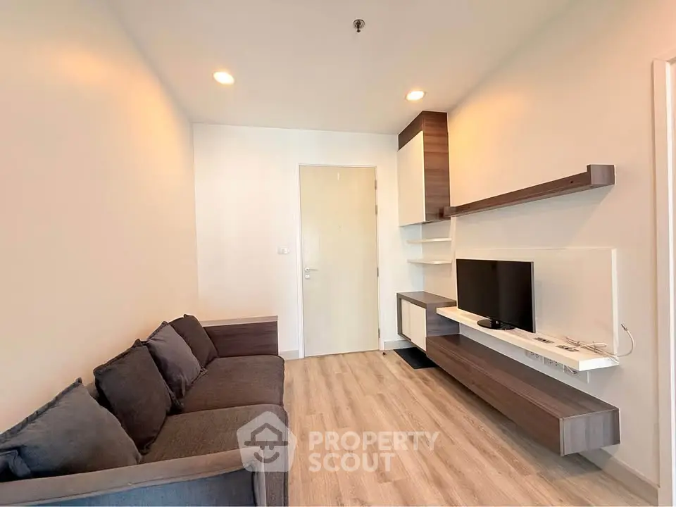 Modern living room with sleek furniture and wall-mounted TV in a cozy apartment.