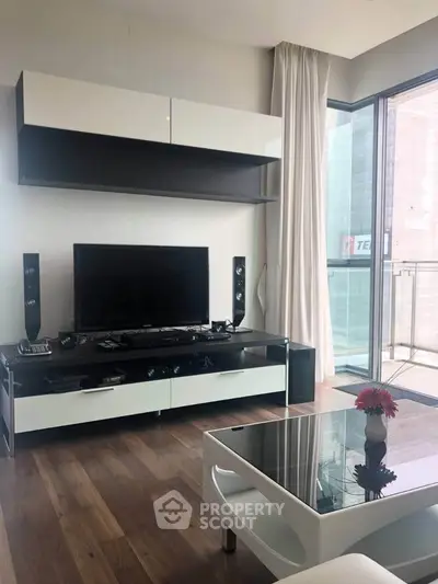 Modern living room with sleek furniture and large glass doors leading to a balcony.