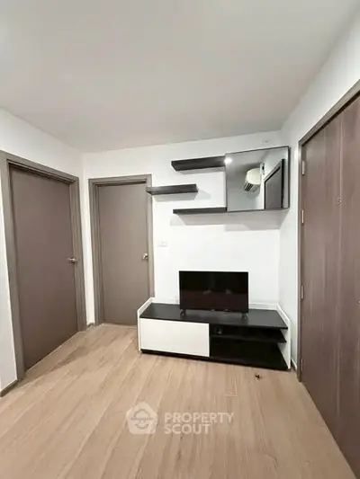 Modern living room with sleek TV stand and floating shelves, showcasing minimalist design and ample storage.