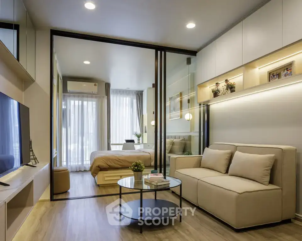 Modern open-plan living room with sliding glass doors leading to a cozy bedroom, featuring stylish decor and natural light.