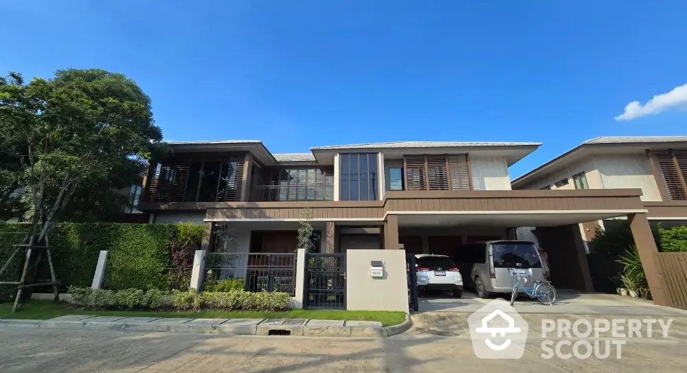 Modern two-story house with spacious driveway and lush greenery in a serene neighborhood.