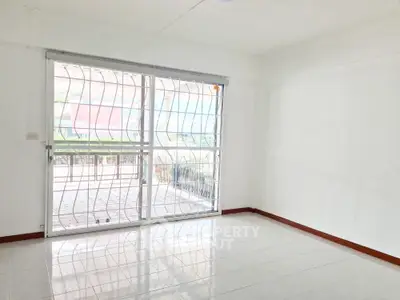 Spacious empty room with large window and tiled floor, perfect for customization.