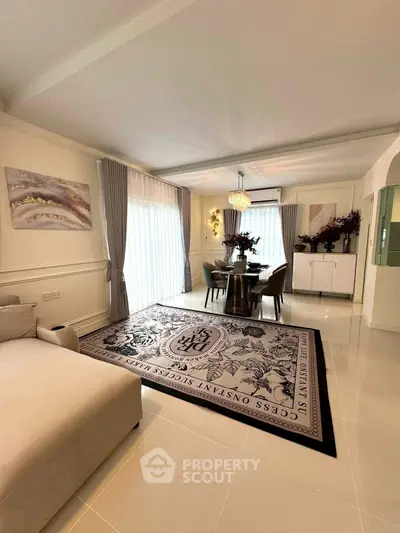 Elegant living room with stylish decor and dining area, featuring large windows and modern furnishings.