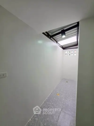 Compact utility room with skylight and tiled floor, ideal for storage or laundry use.