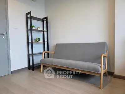 Modern minimalist living room with sleek grey sofa and stylish shelving unit.