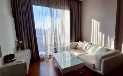 Bright living room with large window and modern white sofa, offering city views.