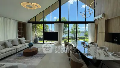 Luxurious living room with stunning lake view, modern furniture, and elegant lighting in a high-ceilinged space.