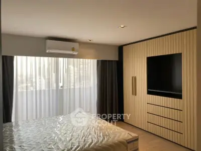 Modern bedroom with built-in wardrobe and large window offering city views.