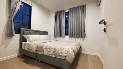 Cozy bedroom with modern decor and ample natural light, perfect for relaxation.