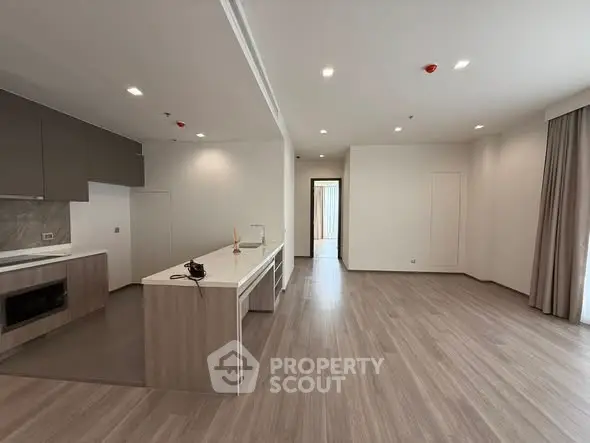 Spacious modern living room with open kitchen and elegant wooden flooring.