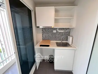 Compact kitchen with modern design and sleek cabinetry, featuring a stylish backsplash and efficient layout.