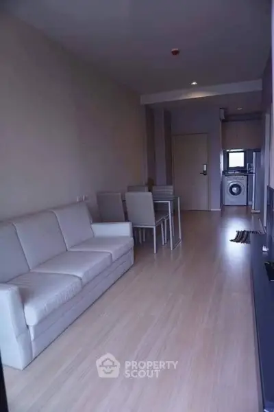 Modern living room with sleek furniture and in-unit washing machine, perfect for urban living.