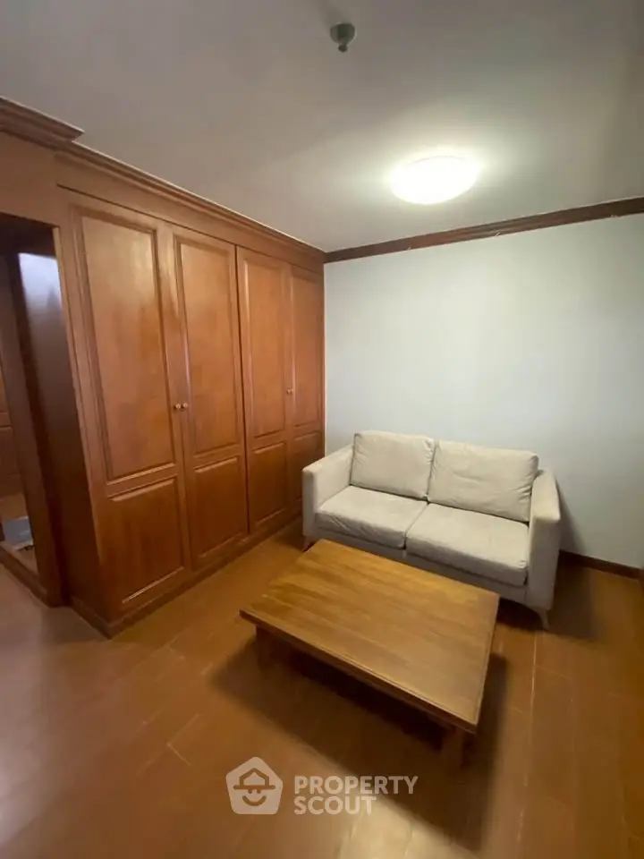Cozy living room with wooden flooring, built-in wardrobe, and comfortable sofa.