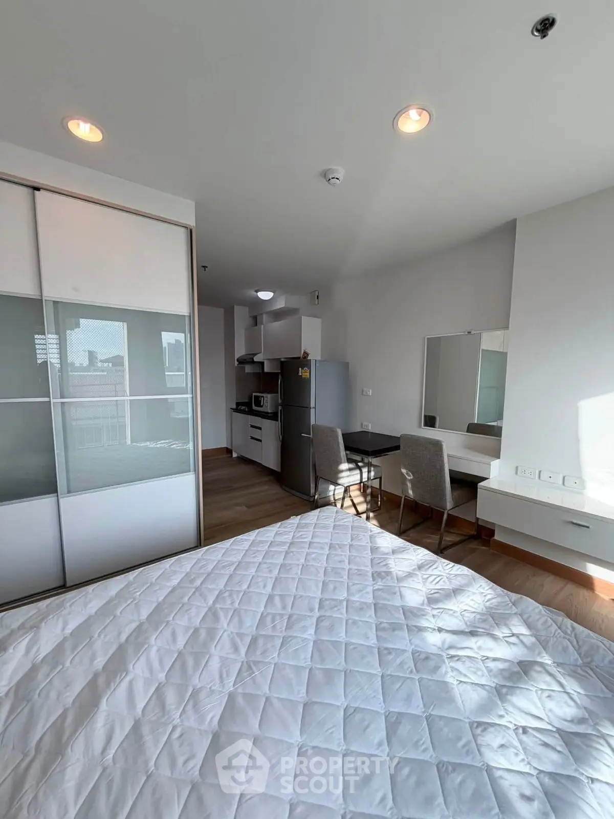 Modern studio apartment with open layout, featuring a cozy bedroom and compact kitchen area.