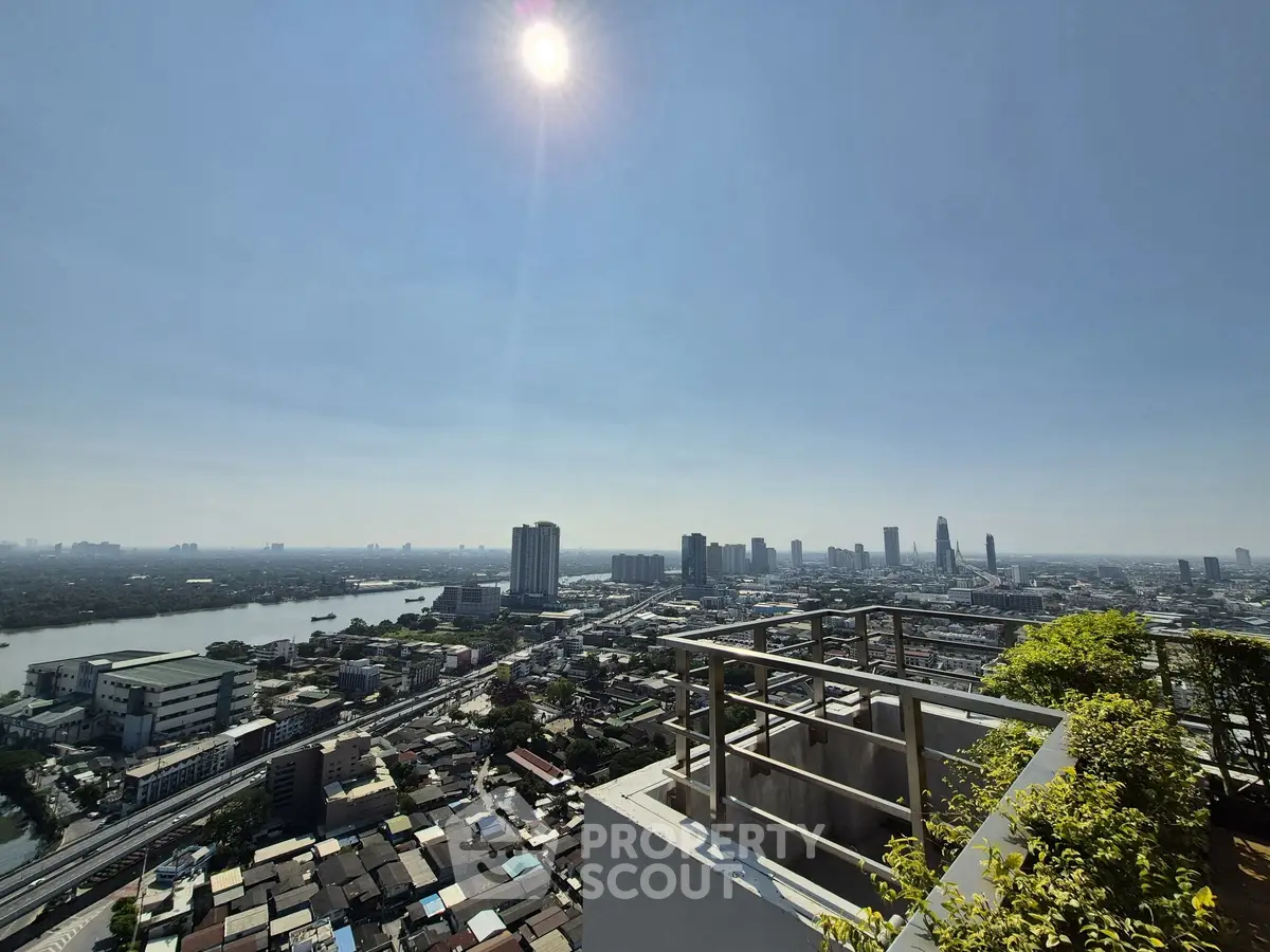 Stunning cityscape view from a high-rise balcony with lush greenery and clear skies.