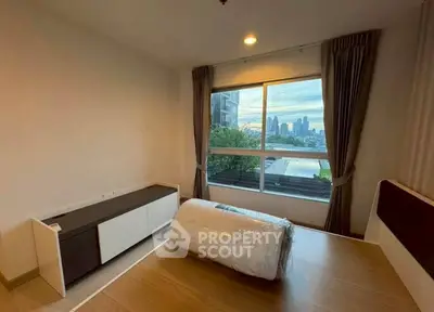 Spacious bedroom with city view, large window, and modern furniture in urban apartment.