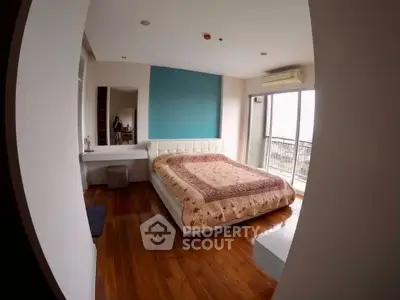 Spacious bedroom with wooden flooring and balcony access in modern apartment