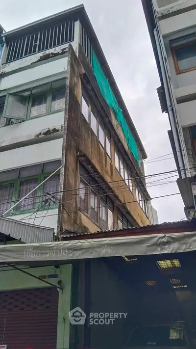 Urban building exterior with weathered facade and green netting, showcasing potential for renovation.