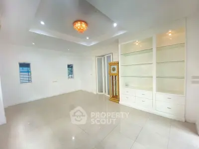 Spacious living room with elegant chandelier and built-in shelves, perfect for modern living.