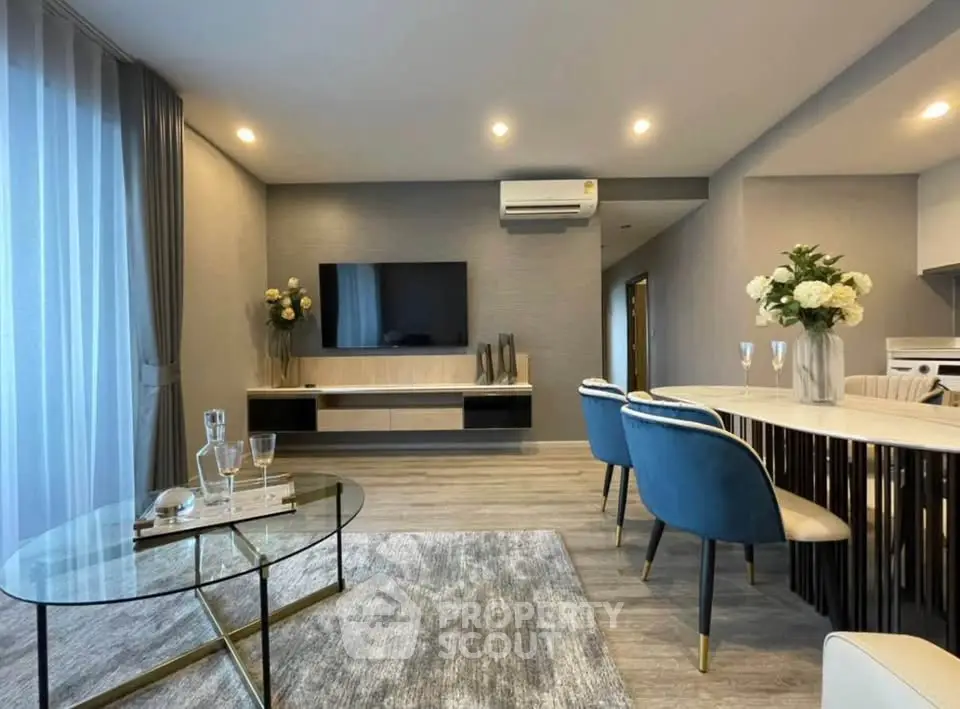 Modern living room with elegant decor and open layout, featuring a sleek TV setup and stylish dining area.
