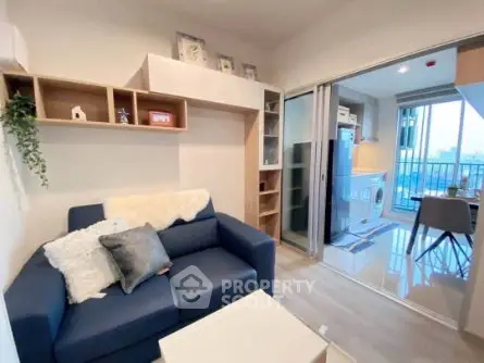 Modern living room with cozy blue sofa and open layout leading to a bright dining area.