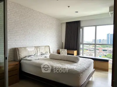 Spacious bedroom with modern decor and large windows offering city views.