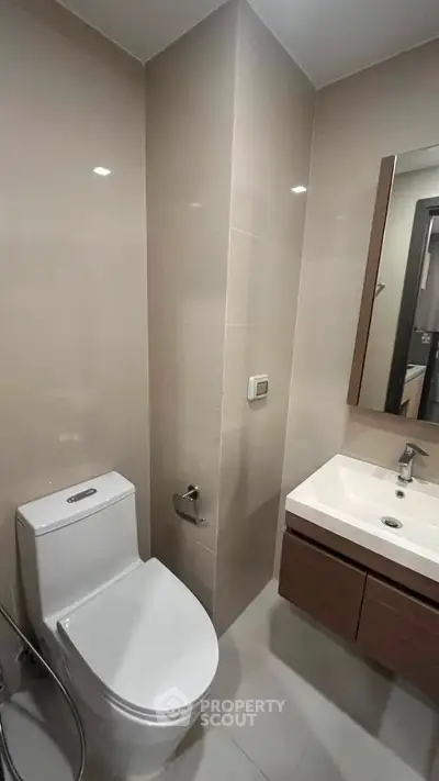Modern bathroom with sleek fixtures and minimalist design, featuring a toilet and vanity sink.