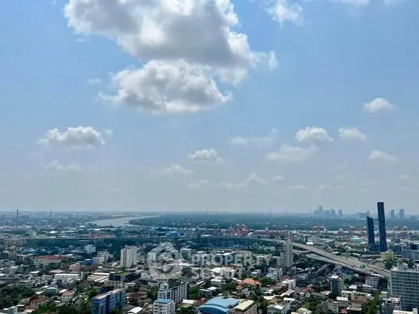 Stunning cityscape view from high-rise building with clear blue sky and scattered clouds.