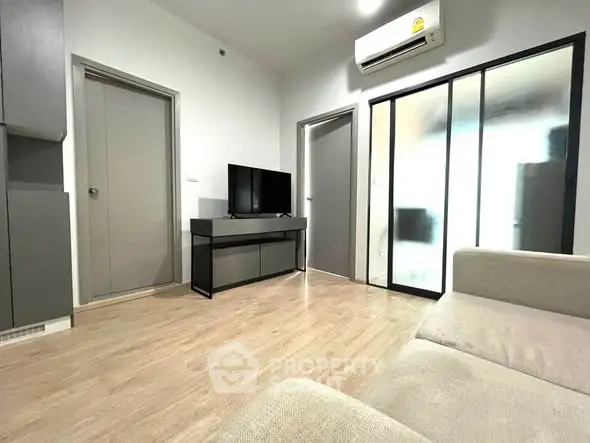 Modern living room with sleek design, featuring a TV and air conditioning, perfect for relaxation.