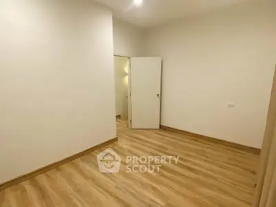 Spacious empty room with wooden flooring and white walls, perfect for customization.