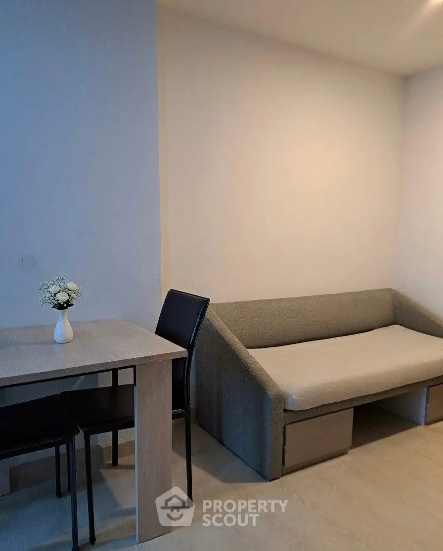Cozy living room with modern sofa and dining table, perfect for small spaces.