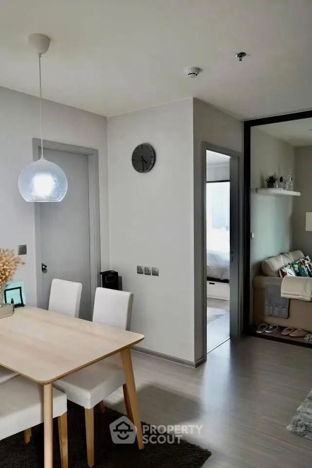 Modern dining area with sleek furniture and cozy living room in open layout apartment.