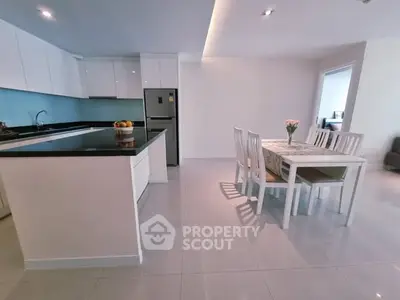 Modern kitchen and dining area with sleek white cabinets and elegant dining table.