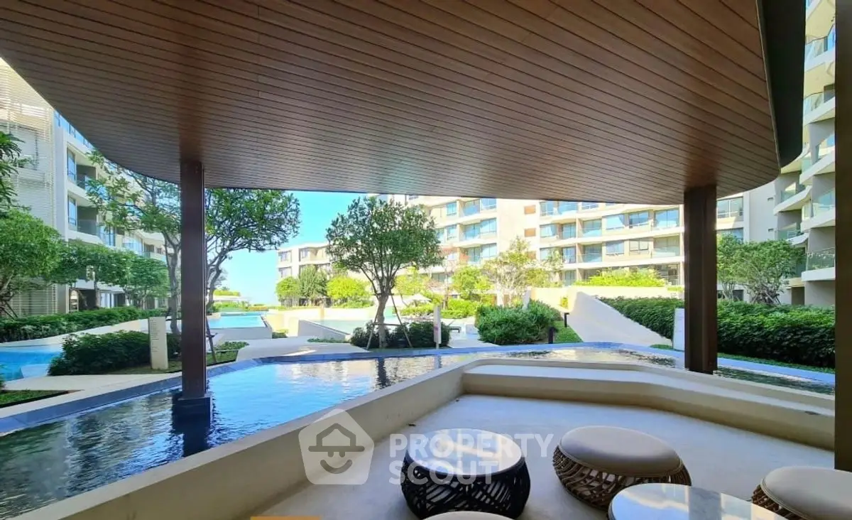 Luxurious modern apartment complex with serene pool and lush greenery.