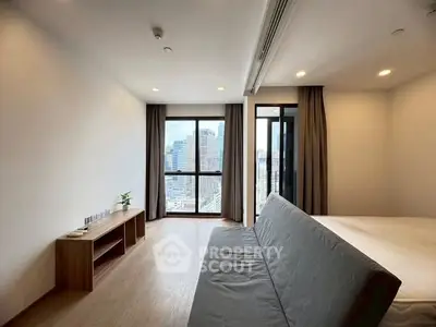 Modern living room with city view, featuring sleek furniture and large windows for natural light.