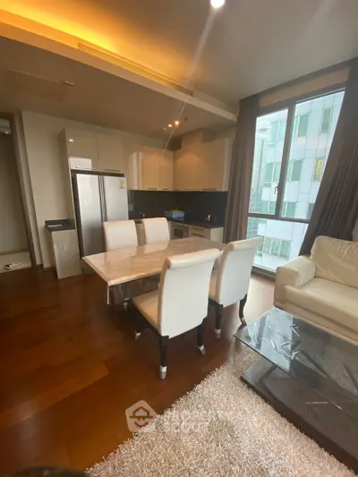 Modern open-layout kitchen and living area with sleek furniture and large windows.
