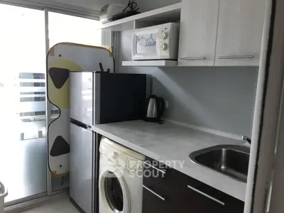 Compact kitchen with modern appliances and washing machine in a cozy apartment.