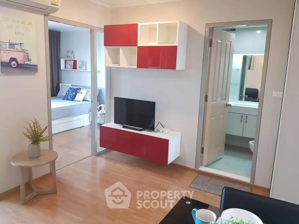 Modern apartment interior with open living room and bedroom, featuring stylish red and white decor.