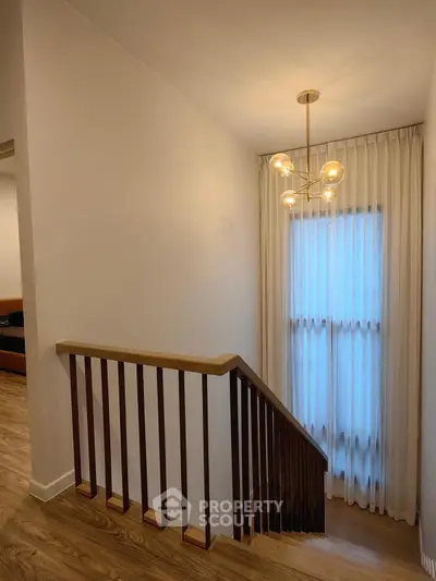 Elegant staircase with modern lighting and wooden railing in a stylish home interior.